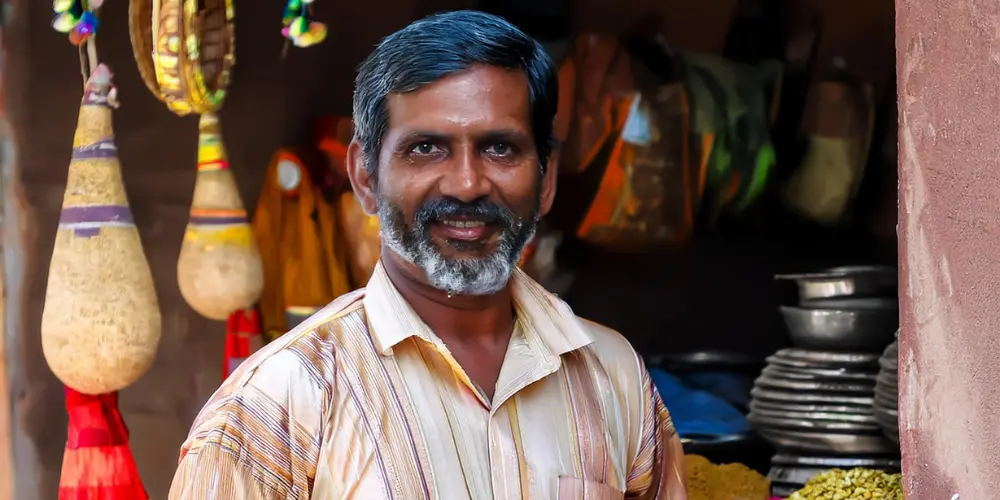 This image depicts a village man in front of his shop.